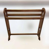 Full view of the wooden display stand showing three horizontal bars and side panels with curved edges.