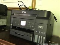 Front-left angled view showing control panel, color LCD, numeric keypad, paper output tray, and front ink tanks.