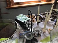 Black metal tealight candle holders and collector spoons on table by window