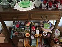 Full view of the vintage wooden table featuring two drawers and various items placed on and beneath it, not included in sale.