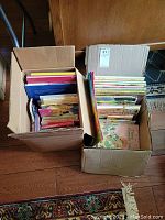 Two large cardboard boxes filled with assorted children's books seen from above and side