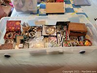 Overview of all jewelry pieces and storage boxes in clear plastic bin