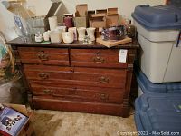 Front and side view of the wooden dresser showing drawers, handles, and objects on top.
