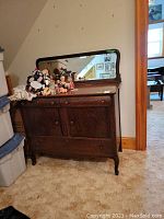Full view of the wood buffet with attached mirror and various dolls on top.