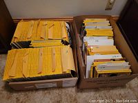 Two cardboard boxes filled with yellow-bordered National Geographic magazines sorted chronologically with paper dividers by year, from 1976 to about 1990.