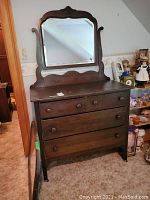 Full view of dark wood dresser with attached curved top mirror, showing three large drawers and two smaller top drawers with wooden knob handles, worn condition