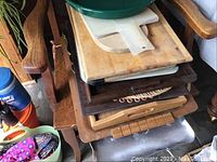 Stack of wooden and plastic cutting boards and trays, showing variety of cutting boards and trays with some wear.
