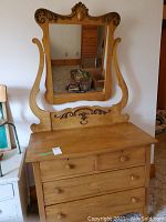 Frontal photo of the wood dresser with attached mirror showcasing the drawer layout and decorative mirror frame.