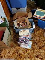 Box with wooden blocks, Lincoln Logs, and various model kit boxes in plastic bins and on carpet