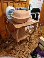Wooden side table with heaters and Romertopf clay roaster displayed on top, showing table design and items