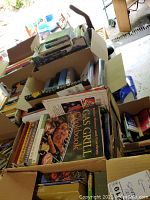 Boxes filled with assorted books including cookbooks, novels, health and gardening books.