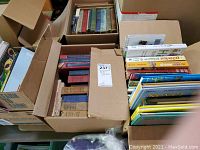 Box with mixed books showing hard and soft bound volumes including chemistry and children's books.