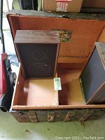 Vintage steamer trunk interior with one speaker inside showing speaker cones and divider.