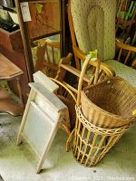 Photo showing two vintage wooden washboards with metal scrubbing surfaces, partially visible wicker baskets, wooden chair and mirror in background.
