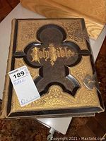 Front cover showing gold embossed title 'Holy Bible' with black and gold decorative insets and two metal clasps.