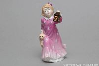 Full frontal view of ceramic figurine showing young girl in pink nightgown, holding lantern and teddy bear.