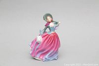 Front angle of Royal Doulton Autumn Breeze porcelain figurine showing detailed face and pink flowing dress with blue accents, holding a white lantern.