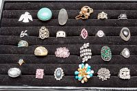 Full display of 25 assorted costume rings arranged in a black foam tray showing variety of styles, colors, and stones.