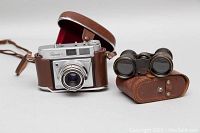 Kodak Ritenette II camera in brown leather case next to Champiere Paris opera binoculars with matching leather case