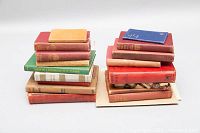 Two stacks of antique books including various red, brown, green cloth bindings, and a small blue book on top