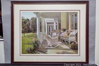 Full view of the large framed print showing the wicker porch furniture and garden background.