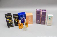 Full lot of assorted ladies perfumes with boxes and open bottles shown on white surface