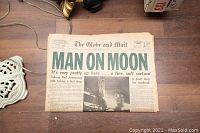 Photo of newspaper with headline 'Man On Moon' showing Neil Armstrong's step on lunar surface