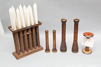 Photo showing wooden candle holder holding twelve white taper candles, and the four antique wooden bobbins arranged side by side.