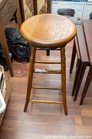 Front view of antique oak industrial stool showing wooden round seat and legs.