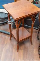 Side angle view showing carved legs and support arches of wooden accent table