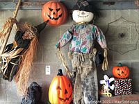 View of Halloween decorations including the scarecrow, witch, two pumpkin decorations, ghost, crow and spider web on garage wall
