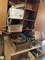 Wooden shelves and counter with assorted tools, boxes containing hardware, and loose cords and wires visible on countertop and shelves.
