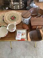 Wood bowls, ceramic cream and sugar set, wooden porcupine toothpick holder, wood and cork coasters, and straw trivets shown on a table