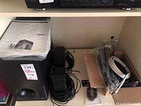 Main view showing Bose Acoustimass 3500 subwoofer with front port, two small satellite speakers, and coiled wires alongside a manual.