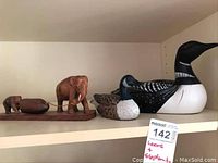 Shelf display of two carved birds (loon and goose) and two carved elephants on wooden base