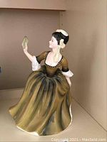 Front view of the Royal Doulton figurine showing the woman holding a fan with detailed dress and face.