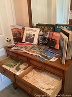 Photo showing a collection of Canadian nature and regional books with a ceramic beer stein on a wooden dresser.