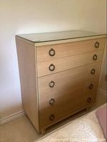 Front view of tall boy wood dresser with glass top and 5 drawers with metal ring handles.