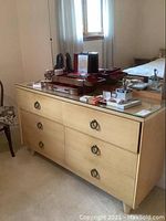 Front view of light wood dresser with 6 drawers and mirror, showing metal ring pulls and glass top surface, items on top not included.