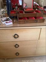 Wooden jewelry box with multiple compartments open and metal necklace stand holding several beaded necklaces in assorted colors such as pink and blue.