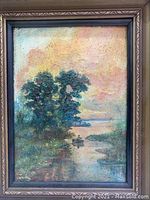 Framed oil on canvas painting with visible texture and hues of orange in sky, blue-green trees, and water with reflection and figure in boat.