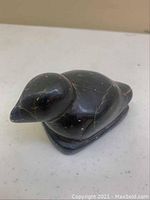 Front side view of black soapstone bird sculpture showing head and body contours with natural stone veins.