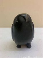 Front view of the black soapstone eagle carving showing the rounded head, body, and small circular eyes.