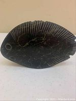 Front view of the dark soapstone fish carving showing carved eyes and fin details