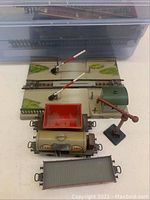 Marklin train pieces including Esso tanker car, green building structure, crossing gates, red crane and flatbed car.