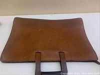 Top view of brown leather portfolio showing handles and surface condition.