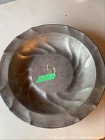 Top view showing the raised swirl design and engraved initials C.K. on the interior base of the pewter bowl.