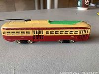 Side view of vintage Bachman TTC train set car with red and cream body, green felt roof, metal wheels, and TTC logo.