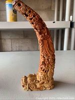 Full side view of curved hand carved stone sculpture with detailed figures and motifs.