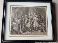 Framed steel engraving featuring a group of people in historic dress inside an architectural hall.